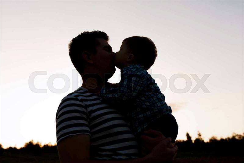 Father and his little son playing outdoors. Boy kisses his dad, stock photo