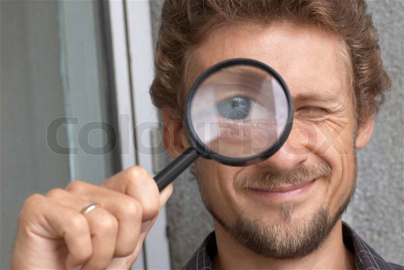 An image of a young man with a magnifying glass, stock photo