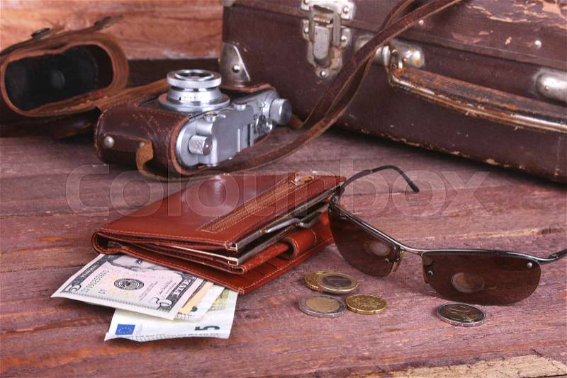 Travel concept with Vintage suitcase, sunglasses, old camera, suede boots, case for money and passport on wooden floor, stock photo