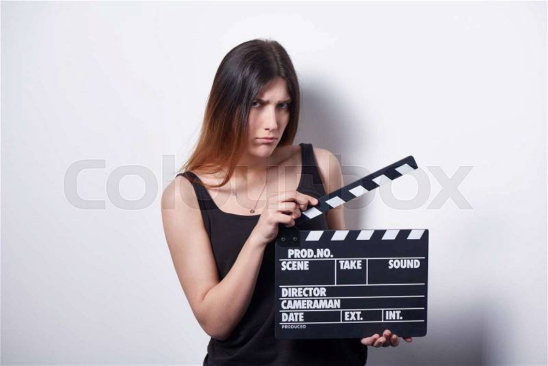 Brooding serious female holding movie clapper board, slate film, stock photo