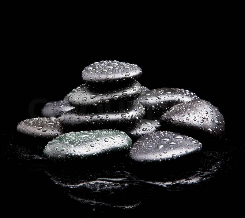 Black shiny zen stones with water drops over black background, stock photo