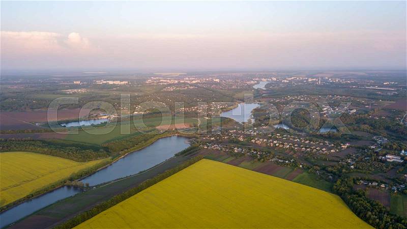Panoramic view from the drone, aerial photography of the landscape with abstract agricultural fields with rape crops and other agricultural crops and prepared for sowing the soil, the infrastructure of the village with rivers and lakes, stock photo