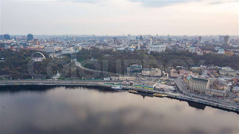Aerial panoramic view from the drone on the central historical part of the city Kiyv, and the district of Podol with the Postal square, hotels, churches, river Port. Reflection of sunset and cloudy sky in the Dnieper River, stock photo
