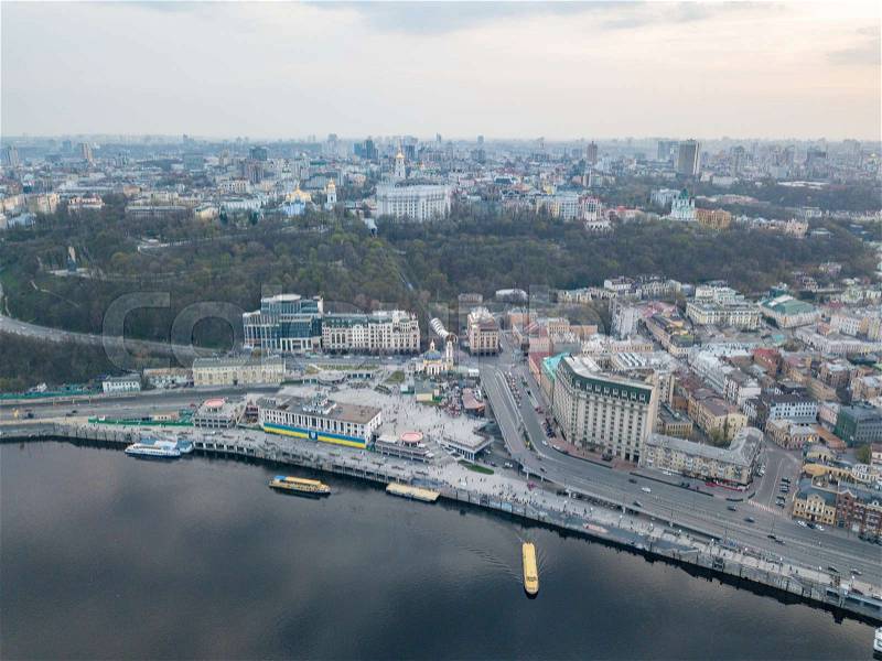 Aerial panoramic view from the drone on the central historical part of the city Kiyv, and the district of Podol with the Postal square, hotels, churches, river Port. Reflection of sunset and cloudy sky in the Dnieper River, stock photo