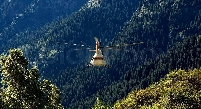 Rescue helicopter flies away in a background of mountains, stock photo