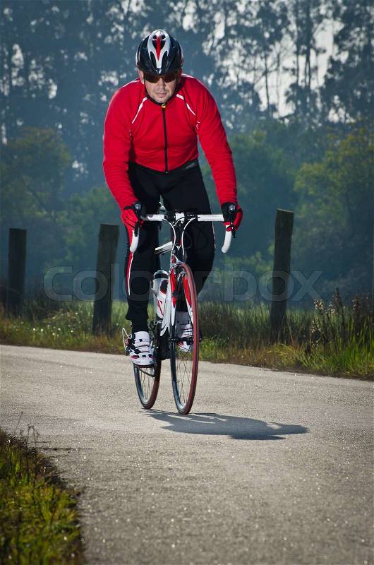 Man on road bike riding down open country road, stock photo