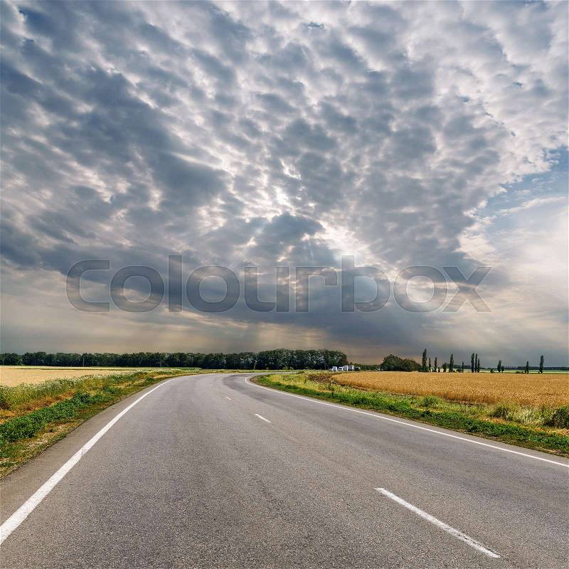 Dramatic clouds over asphalt road to horizon, stock photo