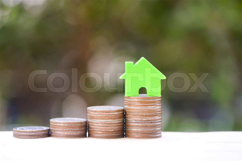Home model on the growing coin stack for concept of money saving for home buying fund, stock photo