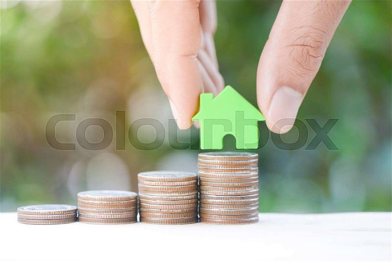 Human hand is put the home model to growing coin stack for concept of money saving for home buying fund, stock photo