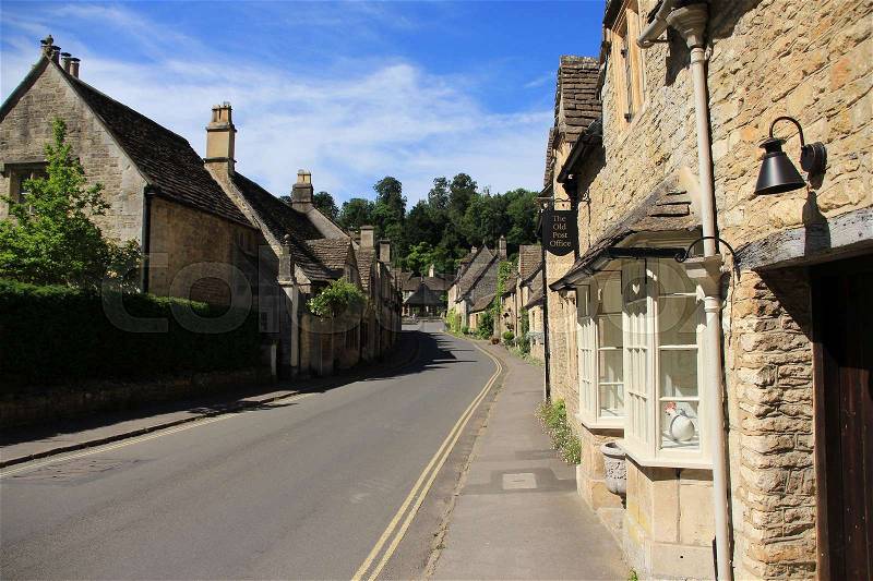 A bell and the old post office in one of the streets with terraced houses in the village Castle Combe in the Cotwolds in England on a sunny day in spring, stock photo