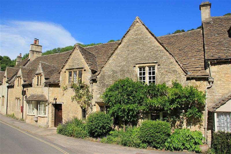 One of the streets with the old post office and terraced houses in the village Castle Combe in the Cotwolds in England on a sunny day in spring, stock photo