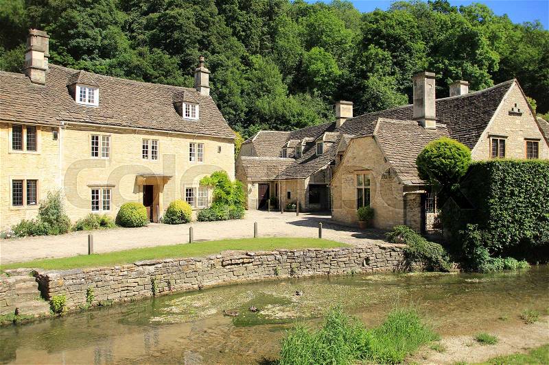 The river and one of the streets with terraced houses in the village Castle Combe in the Cotwolds in England on a sunny day in spring, stock photo