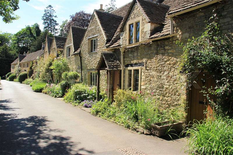 One of the streets with terraced houses in the village Castle Combe in the Cotwolds in England on a sunny day in spring, stock photo