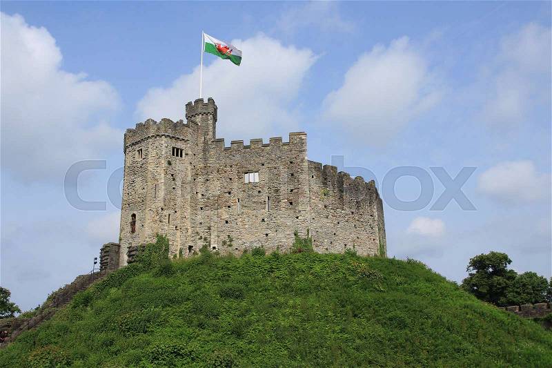 Blue sky with clouds, a waving flag and on the hill Cardiff Castle in the city Cardiff in Wales in spring, stock photo