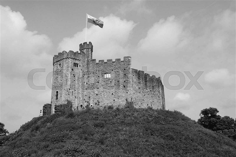 Clouds in the sky, waving flag and on the hill Cardiff Castle in the city Cardiff in Wales in black and white, stock photo