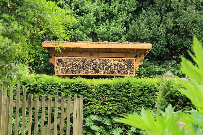 A wooden fence and a bee house with the words, Schools Garden and on the roof xerophyte in the Cambridge University Botanic Garden in the city Cambridge in England on a sunny day in spring, stock photo