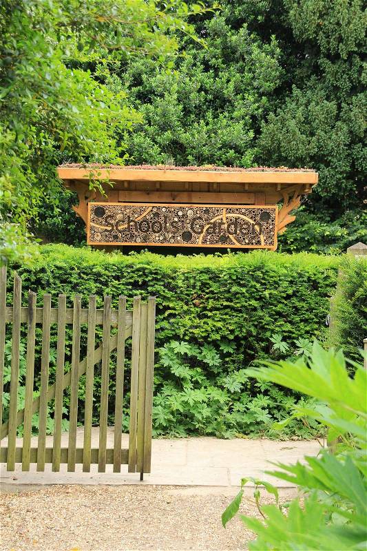 A wooden fence and a bee house with the words, Schools Garden and on the roof xerophyte in the Cambridge University Botanic Garden in the city Cambridge in England on a sunny day in spring, stock photo