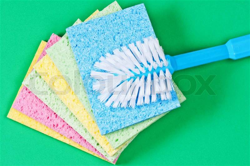 Brush and multi color sponges for cleaning on green background, stock photo