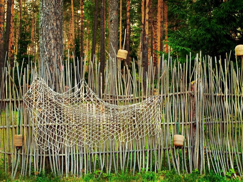 Handmade fence with fishing net in the forest, stock photo