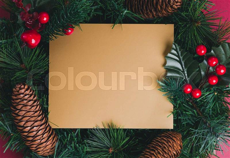 Gold blank greeting card on Green pine christmas wreath with pine cone ,cherry decoration item on red background.Mock up template for adding text or design.Celebration holiday festive concept, stock photo