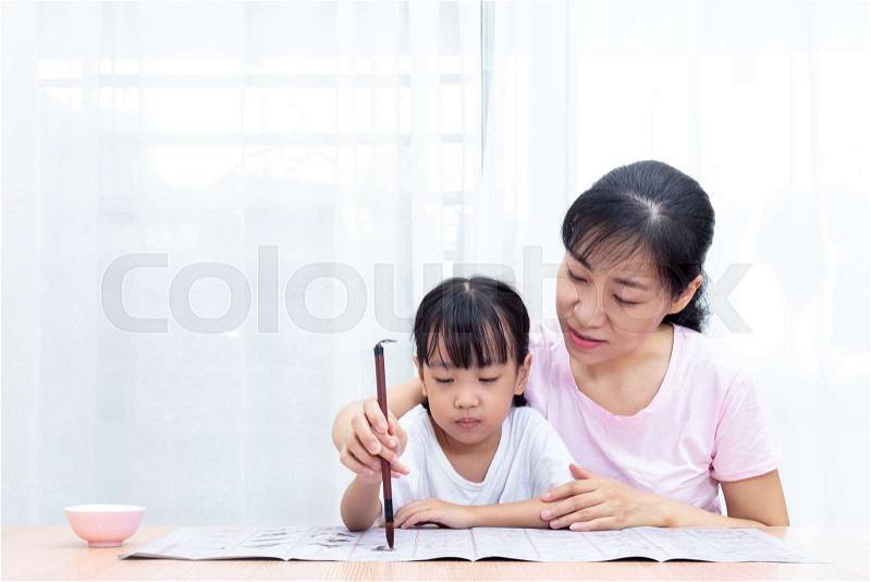 Asian Chinese mother teaching daughter practice Chinese calligraphy at home, stock photo