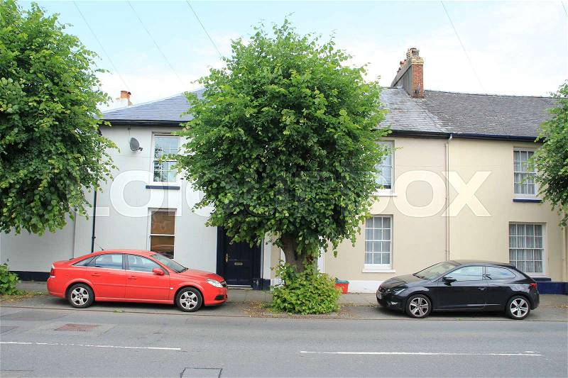 Parking place for the black and red car under the trees before the house in the village Brecon in Wales, stock photo