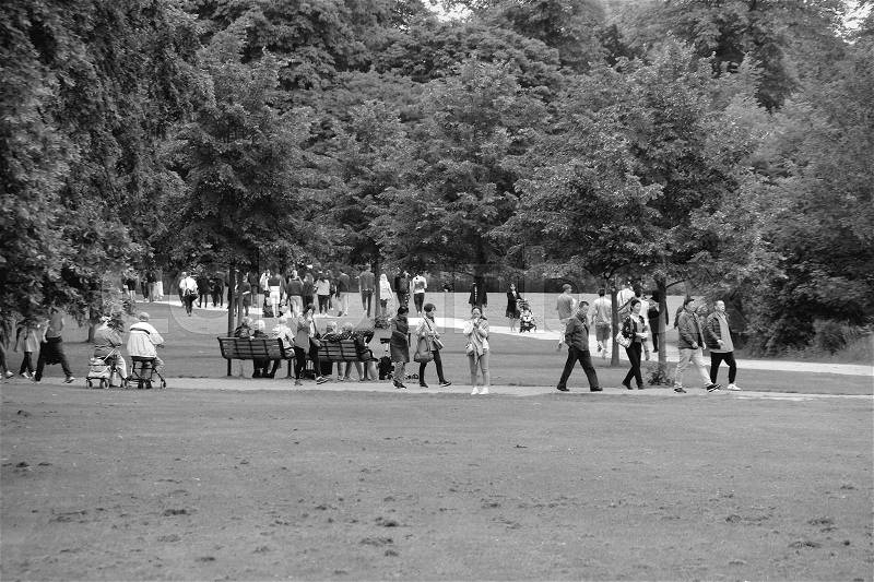 Many people are walking or sitting in the park in the city Cambridge in England on a sunny day in spring in black and white, stock photo