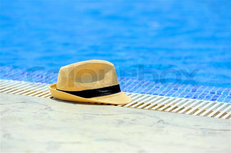 Yellow sun hat on the edge of the pool, stock photo