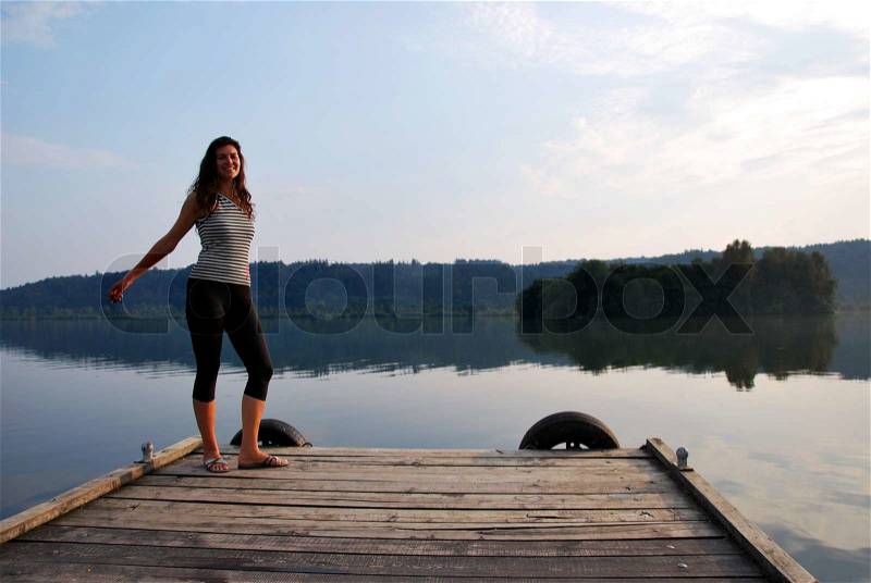 Woman practise aerobic sport at lake pier, stock photo