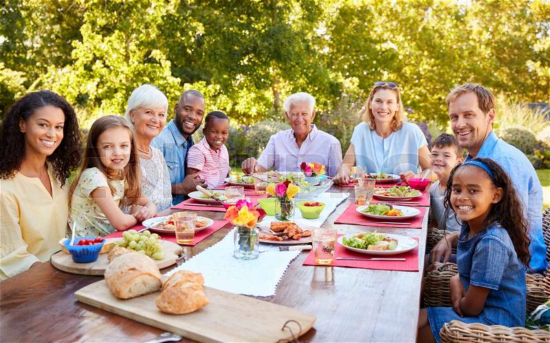 Friends and family having lunch in garden, looking to camera, stock photo
