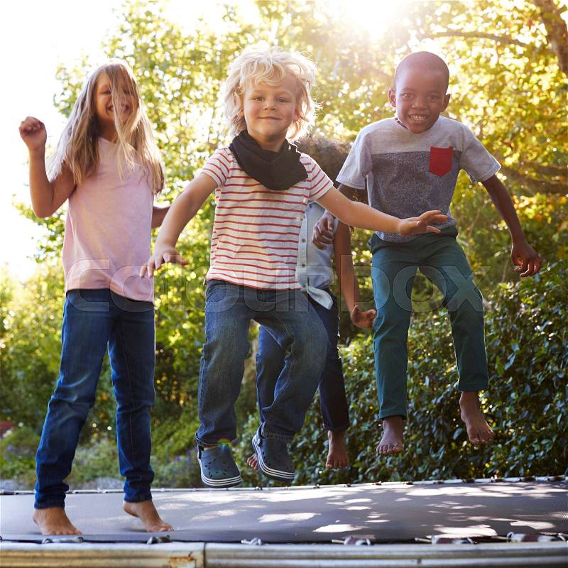Four kids having fun together on a trampoline in the garden, stock photo