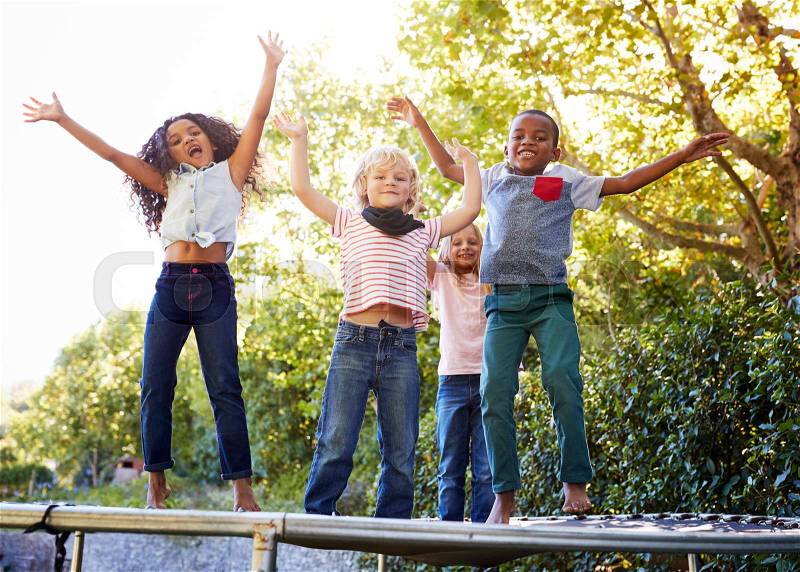 Four kids having fun together on a trampoline in the garden, stock photo