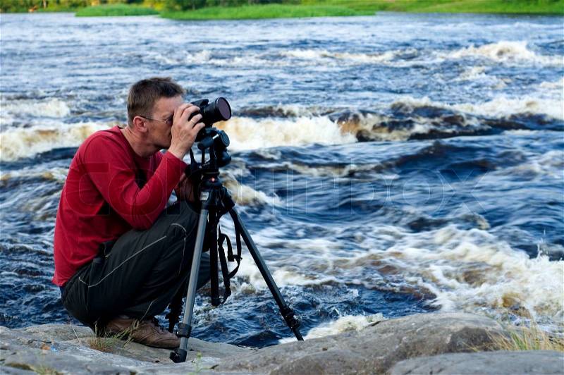 Professional photographer working on river bank, stock photo