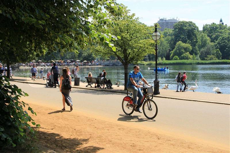 People are walking of biking along the river at Hyde Park in London in England on a sunny day, stock photo
