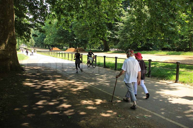 The female runner, a biker and an old couple, wife and the man with a walking stick are at Hyde Park in London in England on a sunny day, stock photo