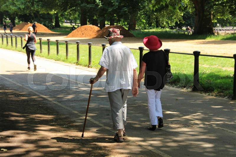The female runner and an old couple, wife and the man with a walking stick are at Hyde Park in London in England on a sunny day, stock photo