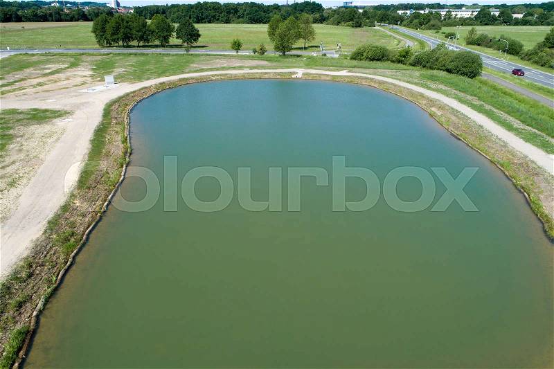 Rainwater retention basin with turquoise coloured water, taken diagonally from the air with a drone, Germany, stock photo