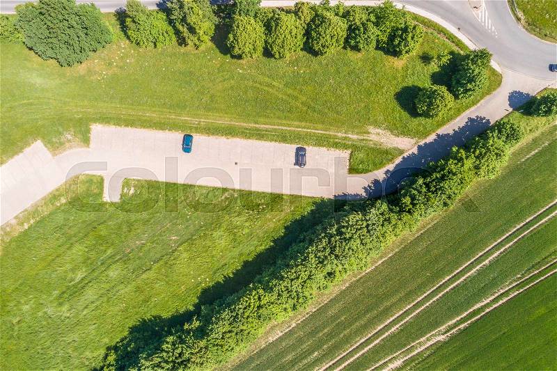 Aerial view of a small parking lot wiping rows of bushes and trees in front of the edge of an arable land, near Wolfsburg, stock photo