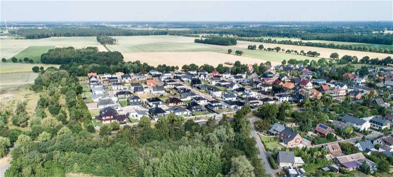 Typical German new housing development in the flat countryside of northern Germany between a forest and fields and meadows, made with drone, stock photo