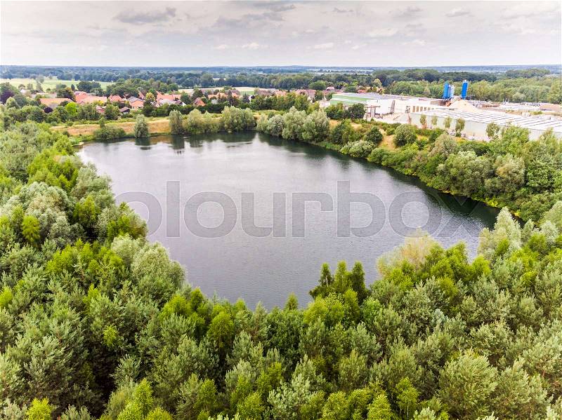 Almost right-angled lake, residual hole of a former sand quarry, surrounded by dense tree population near Gifhorn, Germany, stock photo