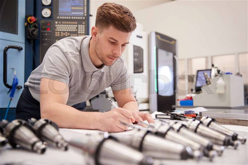 Male Engineer Measuring CAD Drawings In Factory, stock photo