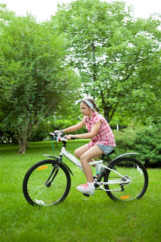 Girl feeling good while riding her bicycle in the park , stock photo