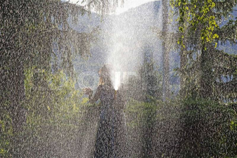 A young woman Watering a lawn in the yard of the house, a background sunlight, stock photo
