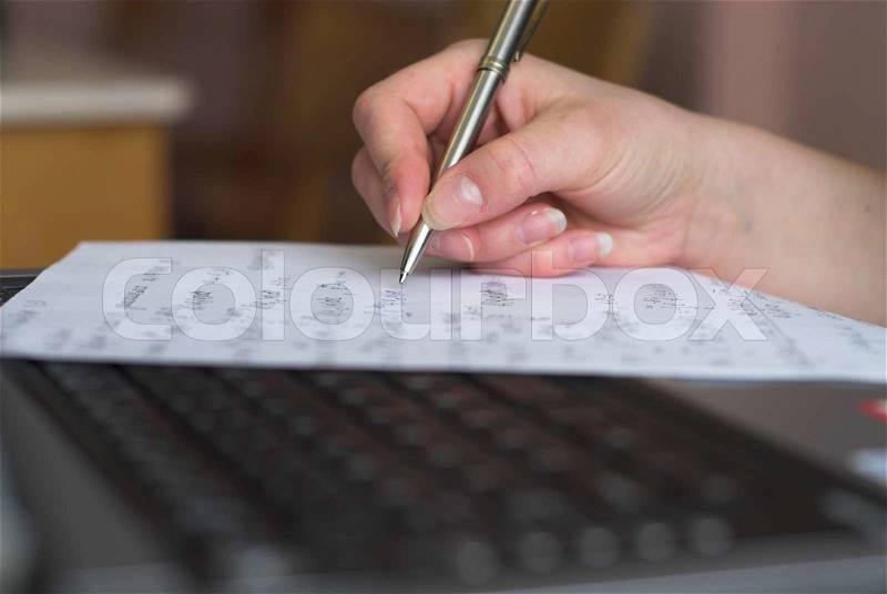Young student is preparing to take a test using pen, papers and laptop, stock photo