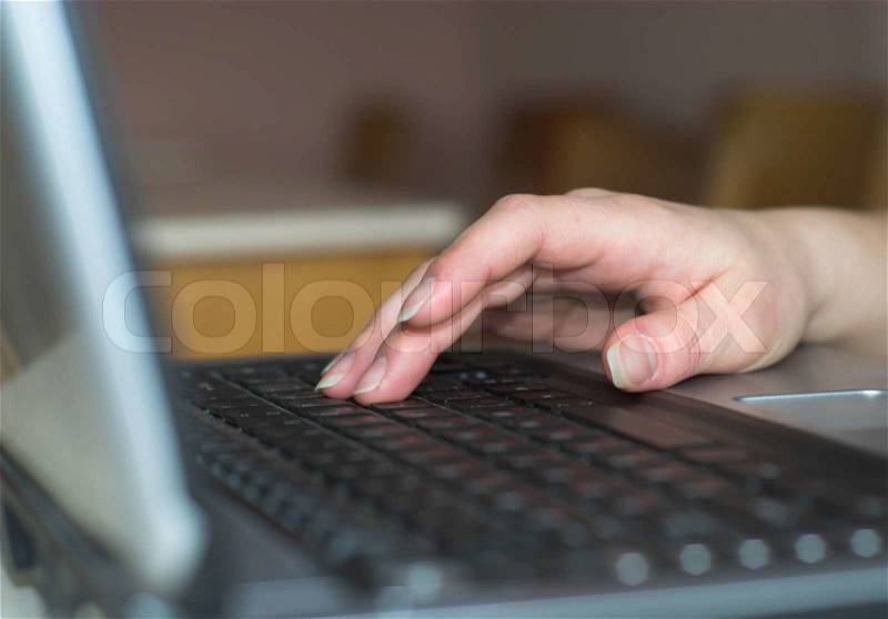 Girls\' finger is pressing on laptops\' keys. Fingersd in focus, stock photo