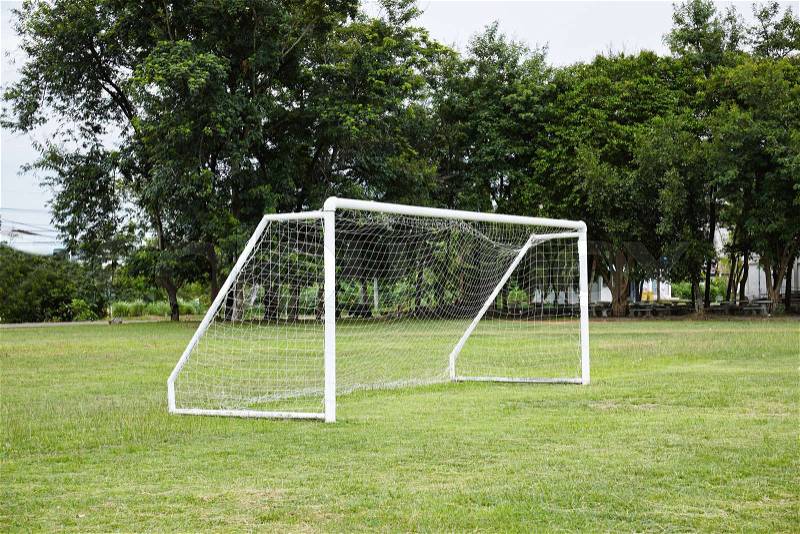 Empty white football, soccer goal with net on the football grass fields in school with tree background, stock photo