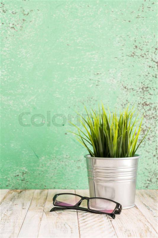 Wooden workplace desktop with plants and glasses; on wooden table, stock photo