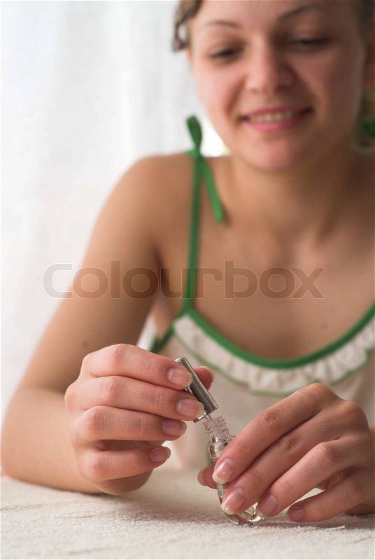 Young female is holding varnish in her hands and smiling, stock photo