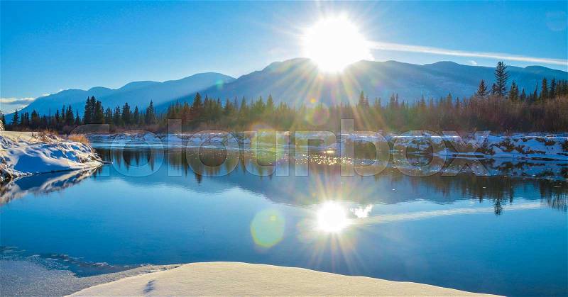 Sun reflection in the water of the Columbia River in Fairmont Hot Springs, British Columbia. Purcell Mountains at sunset, stock photo