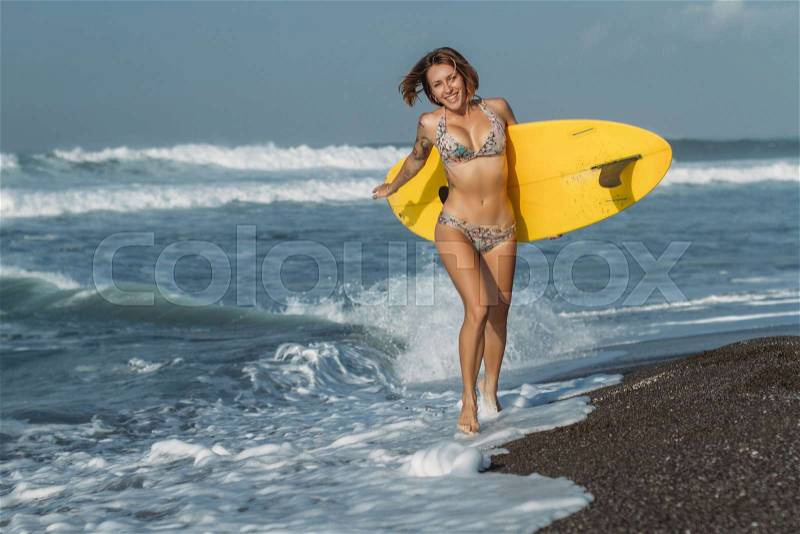 Beautiful girl in bikini running on beach with surf board, stock photo